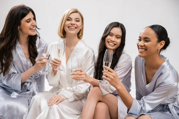 Bridal party, interracial girlfriends holding glasses with champagne, celebration before wedding, brunette and blonde women, bride and her bridesmaids, cultural diversity, positivity, bedroom — Stock Photo