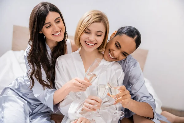 Bridal party, multicultural girlfriends clinking glasses with champagne, celebration, brunette and blonde women, bride and her bridesmaids, cultural diversity, excitement, bedroom — Stock Photo
