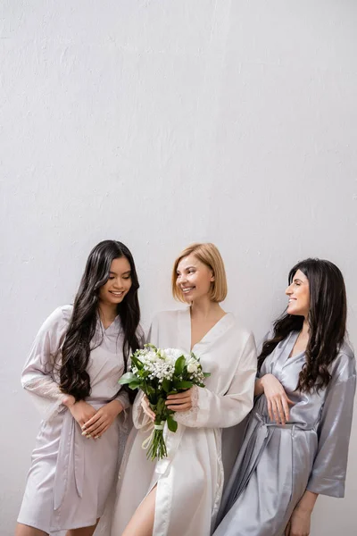 Noiva feliz com flores brancas, damas de honra diversas, buquê de noiva, diversidade cultural, objetivos de amizade, mulheres morenas e loiras, chuveiro nupcial, sorriso e alegria — Fotografia de Stock