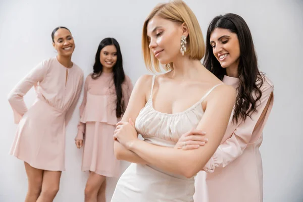 Attractive bride in wedding dress, multicultural bridesmaids on grey background, racial diversity, bridal fashion, style, brunette and blonde, group of women, folded arms — Stock Photo