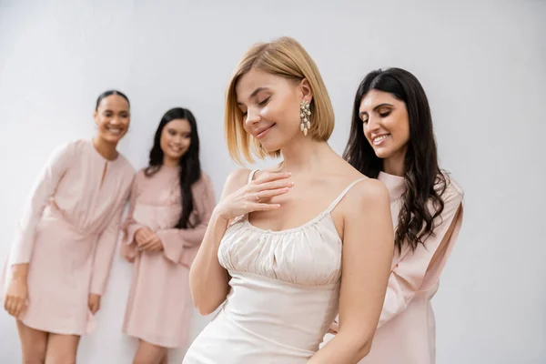 Pleased bride in wedding dress, multicultural bridesmaids on grey background, racial diversity, bridal fashion, style, brunette and blonde, group of women, bridal accessories — Stock Photo