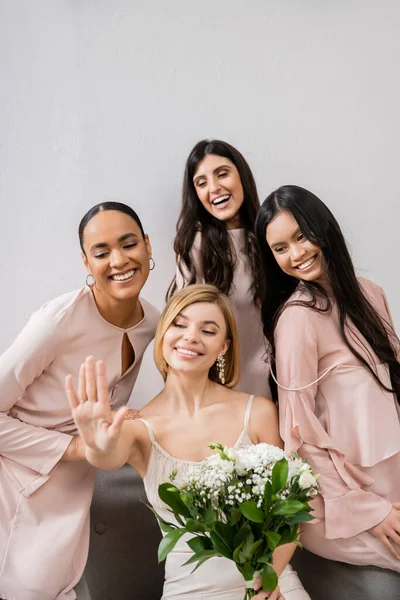 Свадебная фотография, культурное разнообразие, четыре женщины, невеста со своими мультикультурными подружками невесты глядя на обручальное кольцо, брюнетка и блондинка, позитив и радость, праздник — стоковое фото