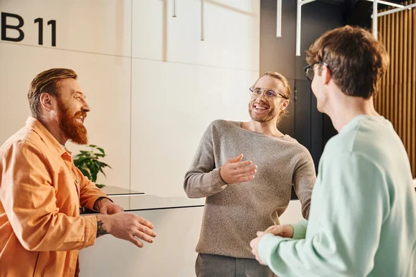 Motivated and excited business partners in stylish casual clothes meeting in hall of contemporary coworking space and discussing startup project, planning and inspiration, productive collaboration — Stock Photo