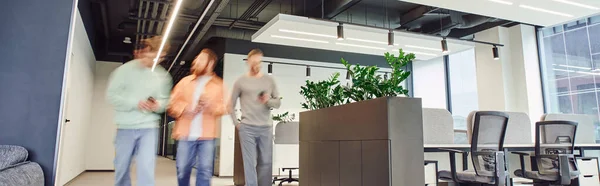 Motion blur of creative business team walking in contemporary coworking space with high tech interior, modern office furniture and green natural plants, partnership and collaboration, banner — Stock Photo