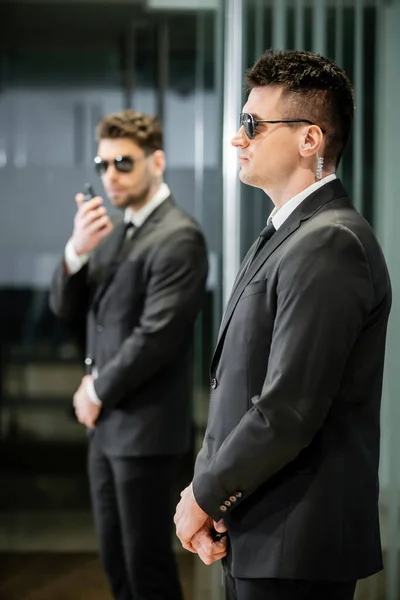 Bodyguard service, private security, professionals in suit and sunglasses standing in hotel lobby, handsome man with earpiece, communication, luxury hotel, vigilance, protection and work — Stock Photo