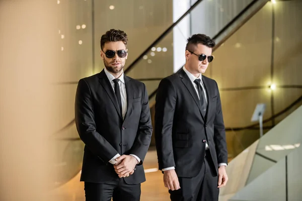 Security management of luxury hotel, two handsome men in formal wear and sunglasses, bodyguards on duty, safety measures, vigilance, suits and ties, private security, strong guards — Stock Photo