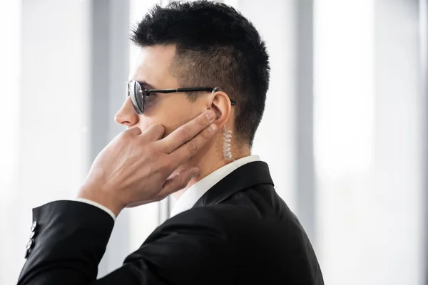 Professional headshots, bodyguard communicating through earpiece, man in sunglasses and black suit with tie, hotel safety, security management, surveillance and vigilance, uniformed guard on duty — Stock Photo