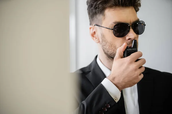 Surveillance, bodyguard communicating through walkie talkie, man in sunglasses and suit with tie, hotel safety, security management, uniformed guard on duty, professional headshots — Stock Photo
