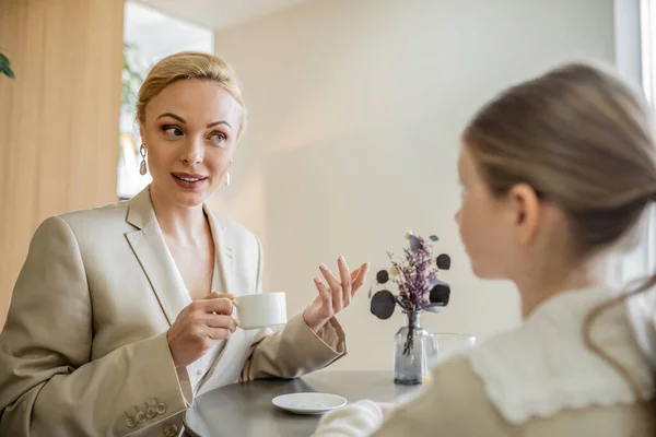 Mother and daughter spending quality time together, blonde woman talking to preteen girl and holding cup of coffee, working parent and kid, modern parenting, family bonding — Stock Photo