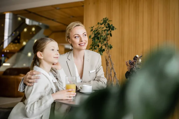 Mutter und Tochter verbringen viel Zeit miteinander, verträumte Blondine spricht mit Frühchen und hält Tasse Kaffee, arbeitende Eltern und Kind, moderne Elternschaft, familiäre Bindung — Stockfoto