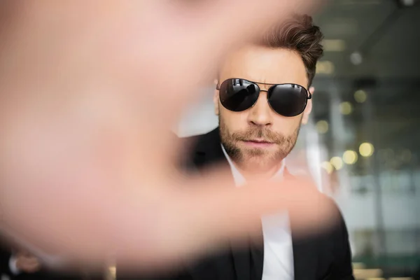 Stop gesture, bodyguard in dark sunglasses and black suit looking at camera, showing stop, hotel safety, security management, uniformed guard on duty, professional headshots — Stock Photo