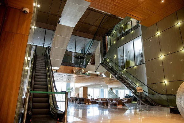 Interior del hotel moderno con diseño sofisticado vestíbulo, escaleras mecánicas, escaleras móviles, sofás de cuero con clase, ambiente lujoso, amplio y confort, elegancia y elegancia, estética - foto de stock