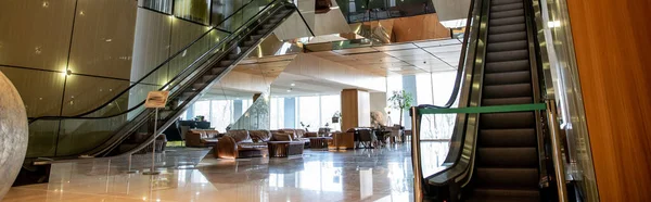 Intérieur moderne de l'hôtel avec design sophistiqué lobby, escaliers mécaniques, escalier mobile, canapés en cuir, ambiance somptueuse, spacieux et confort, chic et chic, esthétique, bannière — Photo de stock