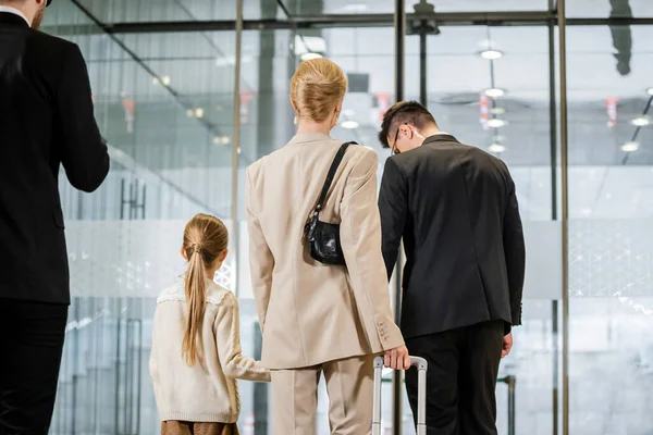 Security service, personal protection, back view of blonde woman and her daughter leaving hotel next to bodyguards, private safety, rich lifestyle, guards on duty — Stock Photo