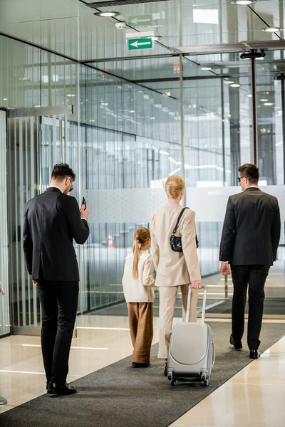 Personal protection, bodyguards in formal wear and sunglasses escorting blonde woman and her daughter, leaving hotel, private safety, rich lifestyle, security service — Stock Photo