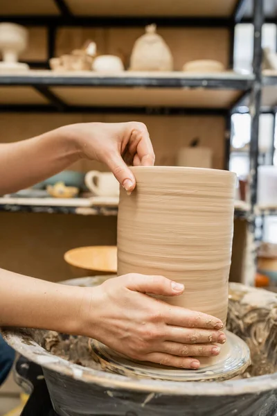 Vista cortada de mãos de artesão fazendo vaso de barro na roda de cerâmica na oficina — Fotografia de Stock