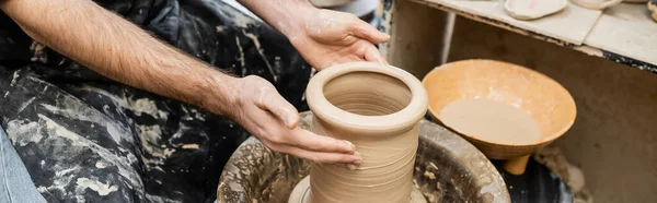 Баннер, Обрезанный вид скульптора, формирующего глину на гончарном круге в керамической мастерской на заднем плане — стоковое фото