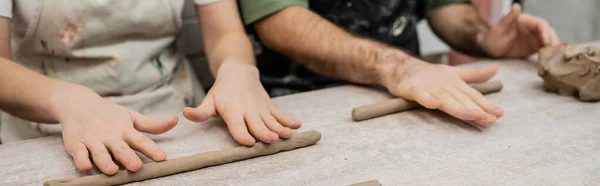 Cropped view of couple of sculptors shaping clay on table while working together in ceramic workshop — Stock Photo