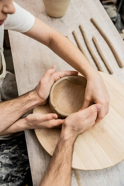 Blick von oben auf romantisches Paar, das in Keramik-Werkstatt gemeinsam Tonschüssel formt — Stockfoto