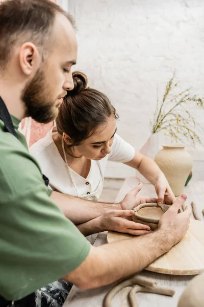 Handwerkerin in Schürze formt mit Freund Tonschale in Keramik-Werkstatt — Stockfoto