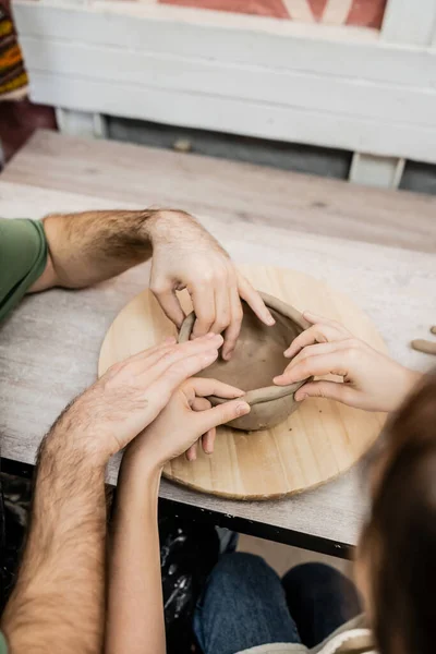 High angle view of romantic couple of artisans making clay bowl together in ceramic workshop — Stock Photo
