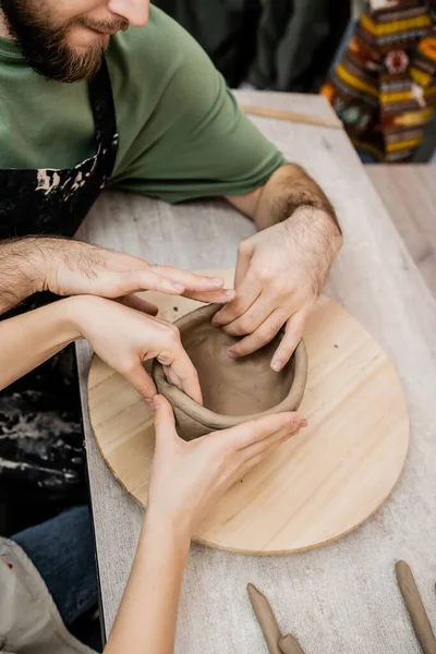 High angle view of couple of potters shaping clay bowl on wooden board in workshop — Stock Photo