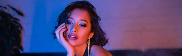 Trendy junge asiatische Frau mit Make-up und Frisur steht im Neonlicht in Nachtclub, Banner — Stockfoto