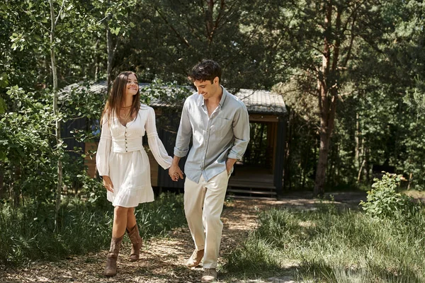 People and nature, positive man and woman in sundress holding hands, walking outdoors, summer — Stock Photo