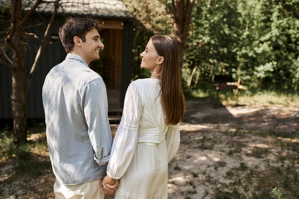 Happy man and woman in white sundress holding hands, looking at each other, summer getaway, romance — Stock Photo