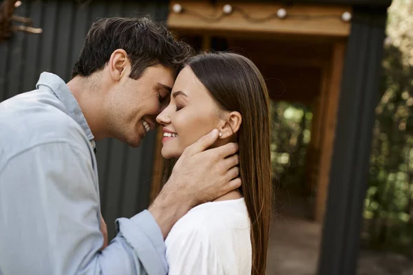 Happy man with closed eyes kissing beautiful girlfriend, vacation house, summer getaway, romance — Stock Photo