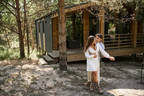 Felicidad y risa, hombre abrazando mujer cerca de casa de vacaciones, en el bosque, el verano y el romance — Stock Photo