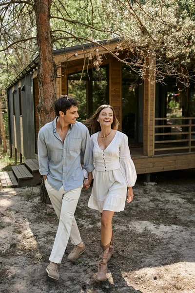 Glückliche Frau Händchen haltend und mit lächelndem Freund spazieren, Paar in der Nähe von Sommerhaus, Romantik — Stockfoto