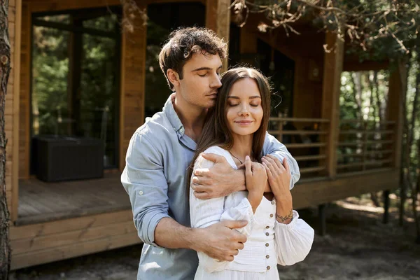 Man hugging beautiful woman in sundress, couple standing near vacation house, people and nature — Stock Photo