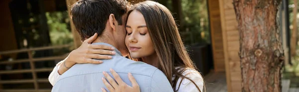 Jovem mulher com olhos fechados abraçando namorado morena perto de casa de férias ao ar livre, banner — Fotografia de Stock