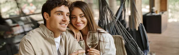 Donna bruna sorridente che abbraccia il fidanzato e tiene il vino sulla terrazza della casa per le vacanze, banner — Foto stock