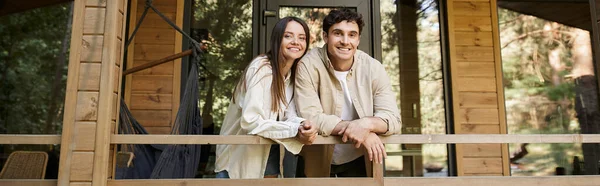 Fröhliches romantisches Paar blickt in die Kamera, während es auf der Terrasse des Sommerhauses steht, Banner — Stockfoto