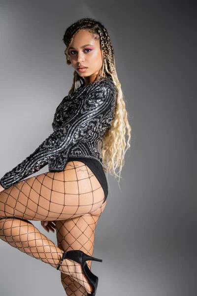 Sexy fishnet tights, bold style, african american woman on grey background, look at camera — Stock Photo