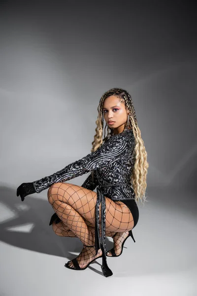 Diversity, dark skinned woman in gloves and fishnet tights, posing on grey background, sexy style — Stock Photo