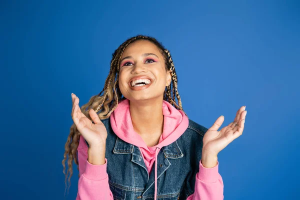 Happy african american woman with dreadlocks laughing and gesturing on blue background, positive — Stock Photo