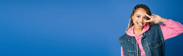 Banner, happy african american woman showing v sign and sticking out tongue on blue background — Stock Photo
