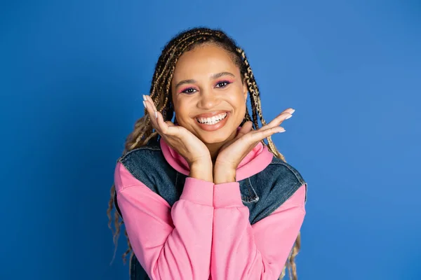 Happy african american woman smiling and looking at camera on blue background, denim vest, style — Stock Photo
