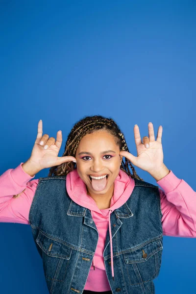 Positivo Africano americano mulher saindo língua no fundo azul, diversão e felicidade, alegria — Fotografia de Stock