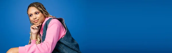 Banner, dreamy dark skinned woman in denim vest and hoodie looking away on blue background — Stock Photo