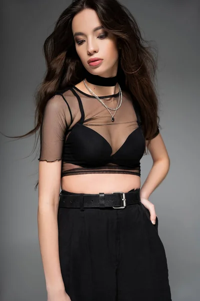 Fashionable young asian woman in mesh top and bra posing while standing isolated on grey — Stock Photo