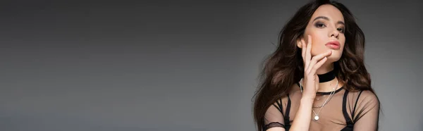 Tendance jeune modèle asiatique avec maquillage portant haut en mesh et colliers isolés sur gris, bannière — Photo de stock