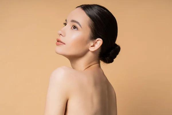 Junge und hübsche asiatische Frau mit perfekter Haut und nackten Schultern steht isoliert auf beige — Stockfoto