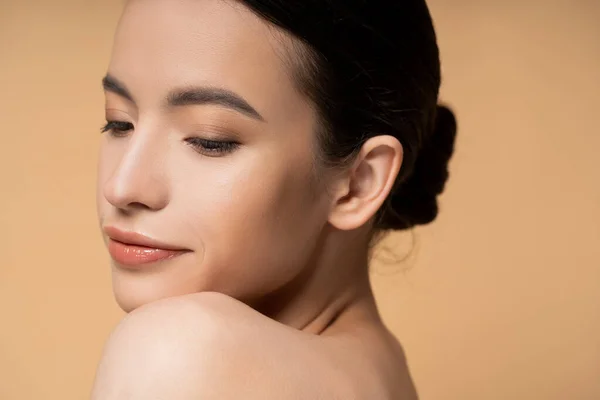 Junge asiatische Frau mit nackter Schulter und natürlichem Make-up posiert isoliert auf beige — Stockfoto