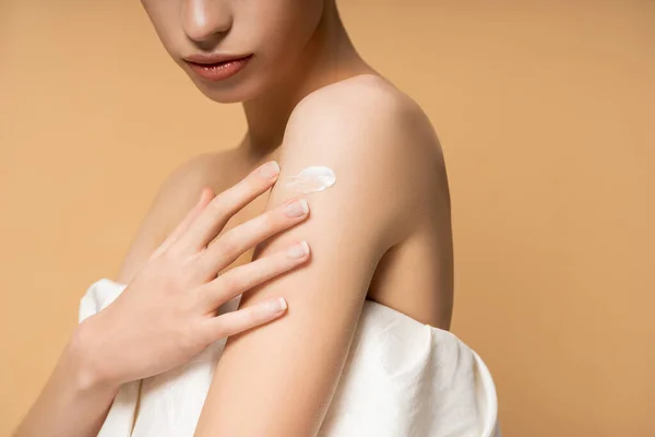 Ausgeschnittene Ansicht der jungen Frau in Top Anwendung kosmetischer Creme auf der Schulter isoliert auf beige — Stockfoto
