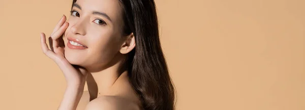 Junge langhaarige asiatische Frau lächelt und schaut in die Kamera isoliert auf beige, Banner — Stockfoto