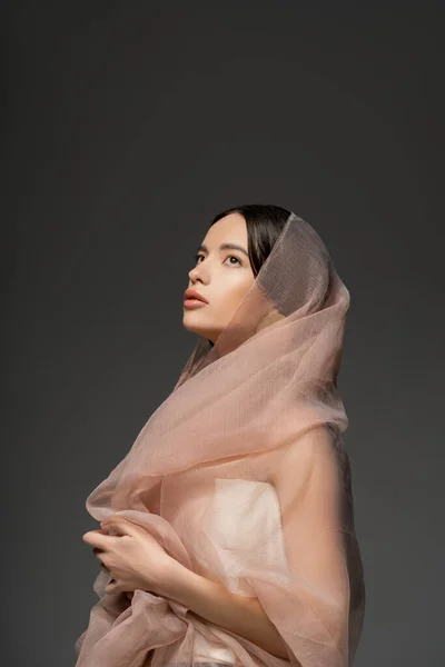 Bella giovane modello asiatico con trucco di tutti i giorni e tessuto beige posa isolato sul grigio — Foto stock